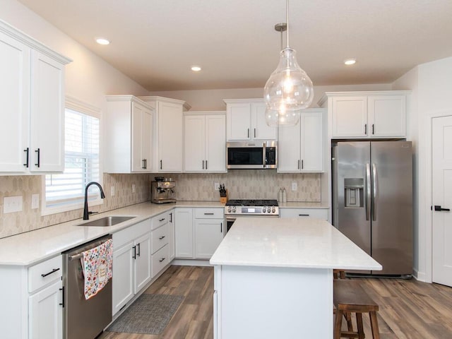 kitchen featuring appliances with stainless steel finishes, a breakfast bar, a center island, white cabinetry, and a sink