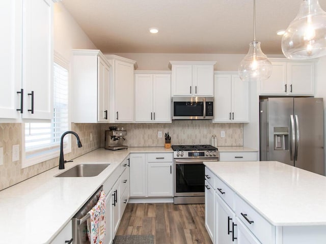 kitchen with dark wood finished floors, stainless steel appliances, tasteful backsplash, white cabinetry, and a sink