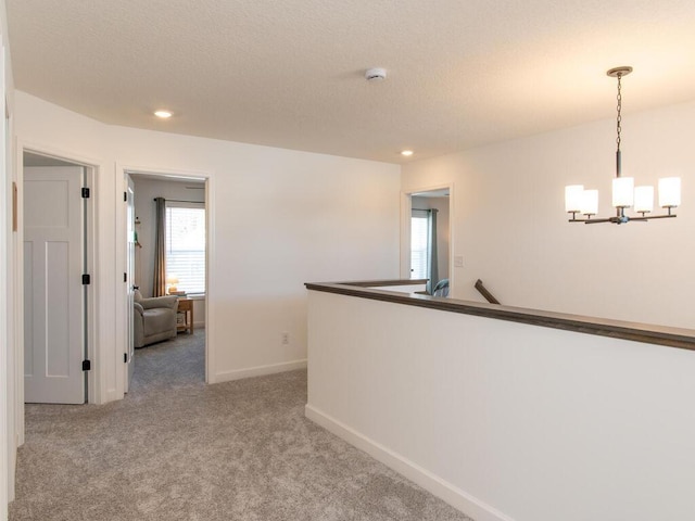 hall with a textured ceiling, recessed lighting, carpet floors, baseboards, and an inviting chandelier