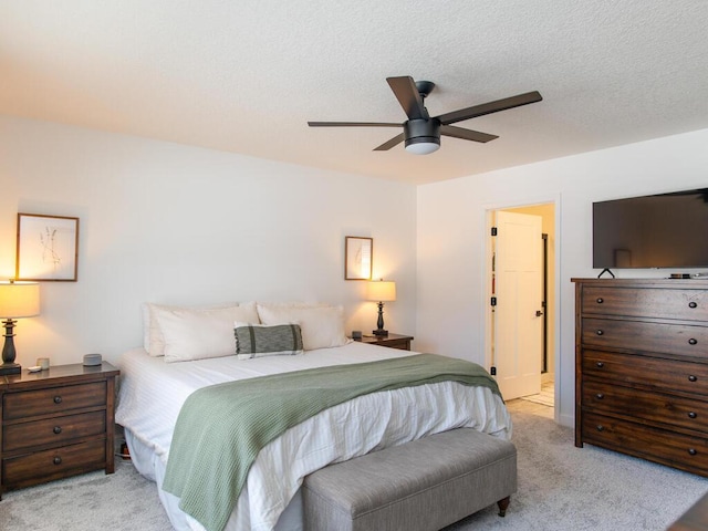 bedroom with a ceiling fan, light carpet, and a textured ceiling