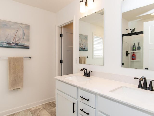 full bathroom with double vanity, a shower with door, baseboards, and a sink