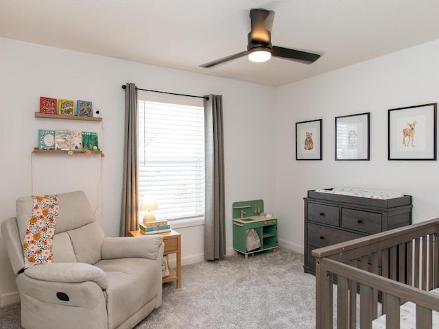 bedroom with baseboards, a crib, a ceiling fan, and light colored carpet