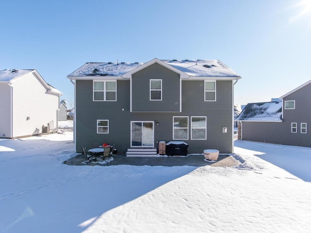 snow covered back of property featuring entry steps