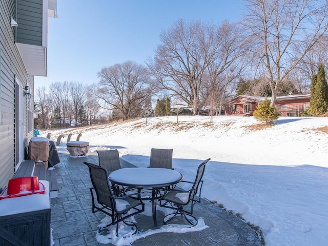 snow covered patio with outdoor dining area and a grill