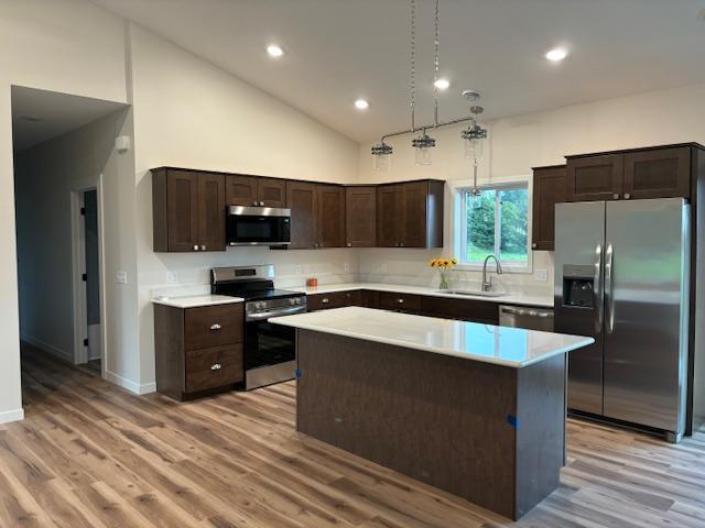 kitchen featuring light wood-style flooring, appliances with stainless steel finishes, light countertops, dark brown cabinets, and a sink