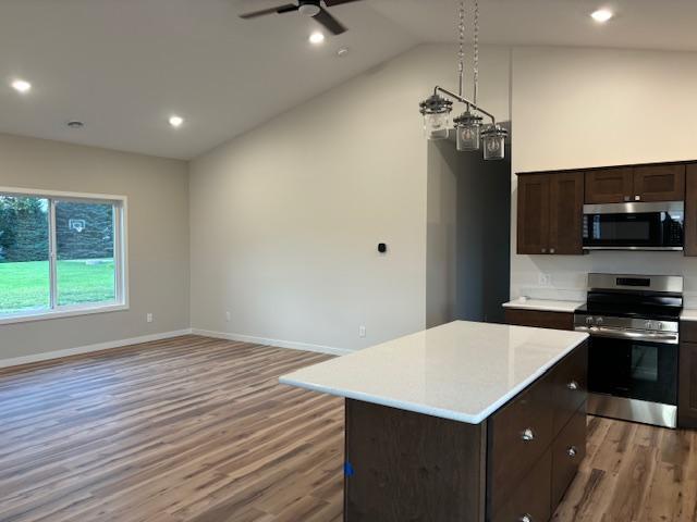 kitchen featuring light wood-style flooring, a center island, vaulted ceiling, stainless steel appliances, and light countertops