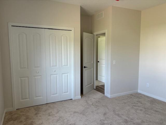 unfurnished bedroom with a closet, carpet, visible vents, and baseboards