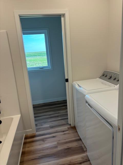 laundry room with laundry area, washer and clothes dryer, wood finished floors, and baseboards