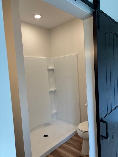 full bath featuring a stall shower, wood finished floors, and toilet