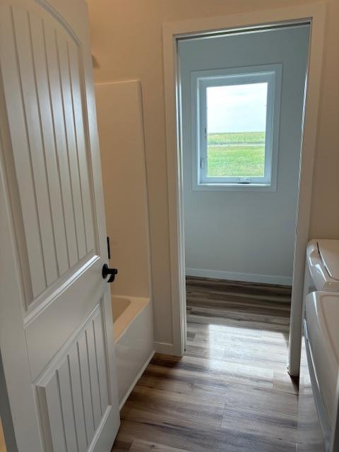 laundry room with laundry area, baseboards, separate washer and dryer, and wood finished floors