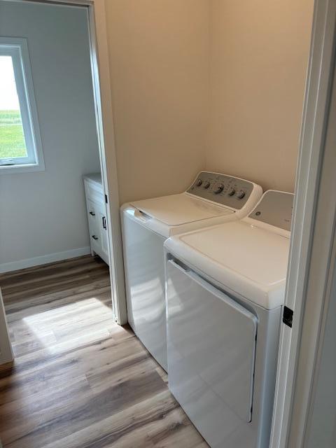 washroom with laundry area, washer and clothes dryer, light wood-style flooring, and baseboards