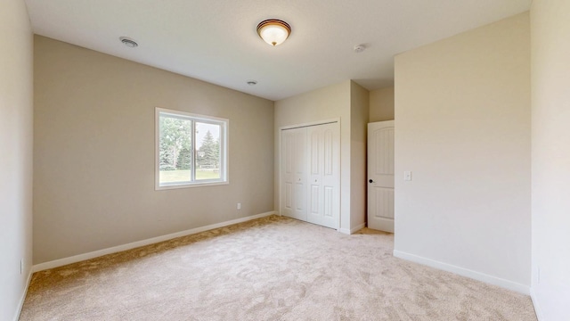 619 6th St, West Concord, MN 55985 - unfurnished bedroom featuring light carpet, baseboards, and a closet