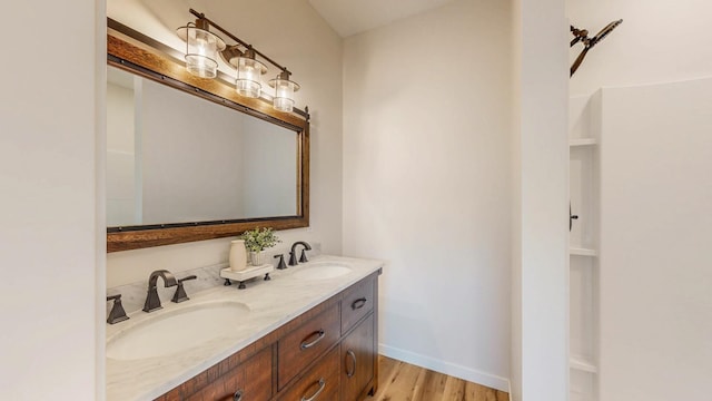 619 6th St, West Concord, MN 55985 - full bathroom featuring wood finished floors, double vanity, and baseboards