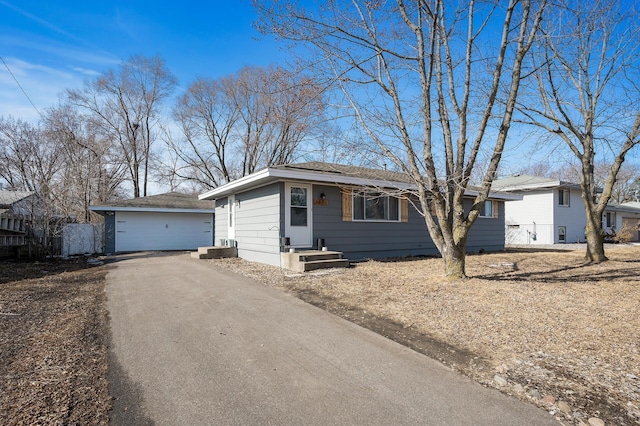 ranch-style home with aphalt driveway, an outbuilding, and fence