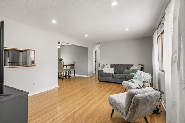 living room with a textured ceiling, recessed lighting, light wood finished floors, baseboards, and ceiling fan