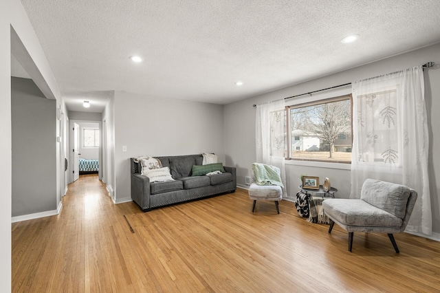 living room with recessed lighting, a textured ceiling, light wood-type flooring, and baseboards