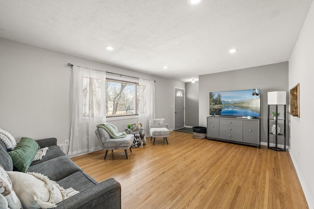 living room with recessed lighting, wood finished floors, baseboards, and a textured ceiling