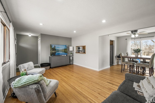 living room with baseboards, recessed lighting, light wood-style floors, a textured ceiling, and a ceiling fan