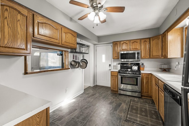 kitchen featuring baseboards, appliances with stainless steel finishes, brown cabinetry, and light countertops