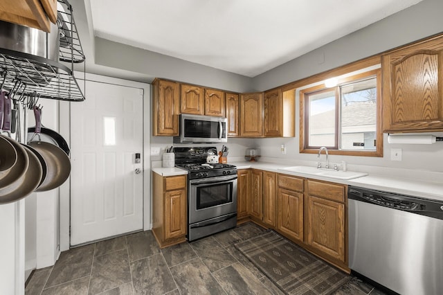 kitchen with brown cabinetry, appliances with stainless steel finishes, light countertops, and a sink