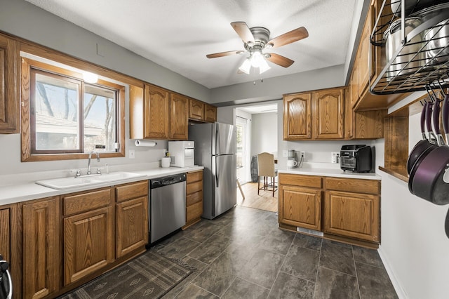 kitchen featuring light countertops, brown cabinetry, appliances with stainless steel finishes, and a sink