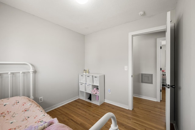 bedroom with wood finished floors, baseboards, and a textured ceiling