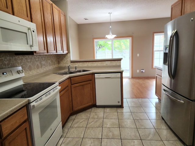 7721 Elm Grove Ave, New Hope, MN 55428 - kitchen with white appliances, a sink, brown cabinetry, tasteful backsplash, and hanging light fixtures