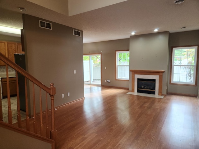 7721 Elm Grove Ave, New Hope, MN 55428 - unfurnished living room with wood finished floors, a fireplace with flush hearth, stairs, baseboards, and recessed lighting