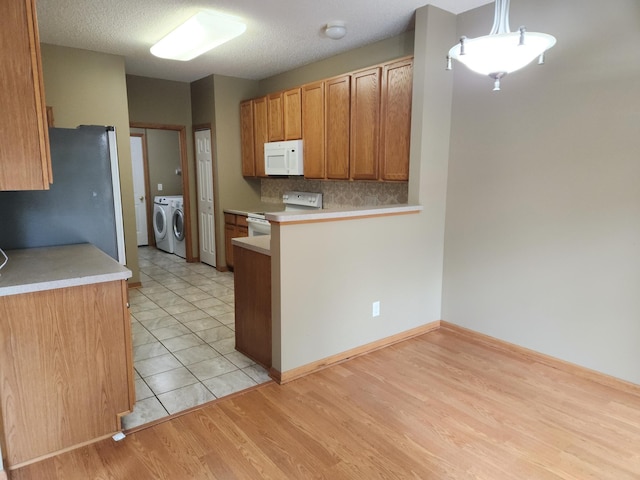 7721 Elm Grove Ave, New Hope, MN 55428 - kitchen featuring white appliances, separate washer and dryer, light countertops, tasteful backsplash, and a peninsula
