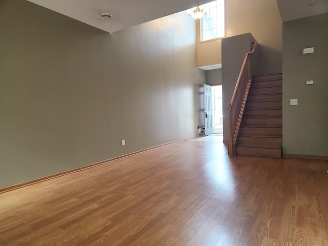 7721 Elm Grove Ave, New Hope, MN 55428 - unfurnished living room with stairs, wood finished floors, a chandelier, a high ceiling, and baseboards