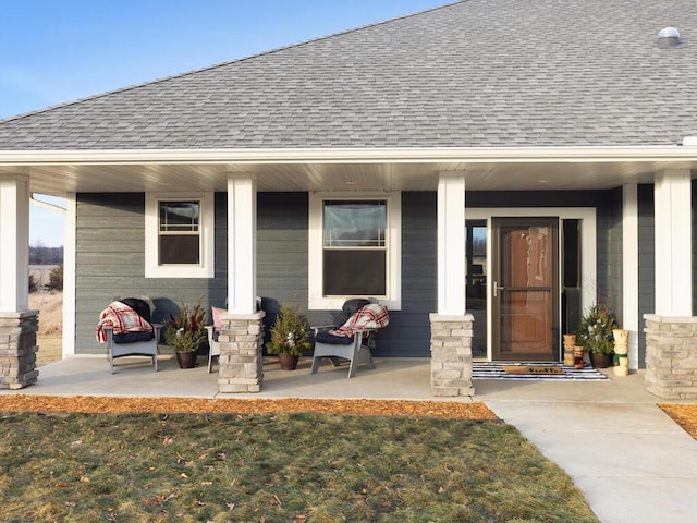 entrance to property featuring a porch, a shingled roof, and a lawn