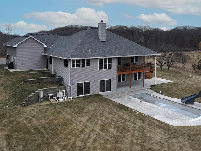 rear view of property with a patio, central AC, a yard, roof with shingles, and a chimney