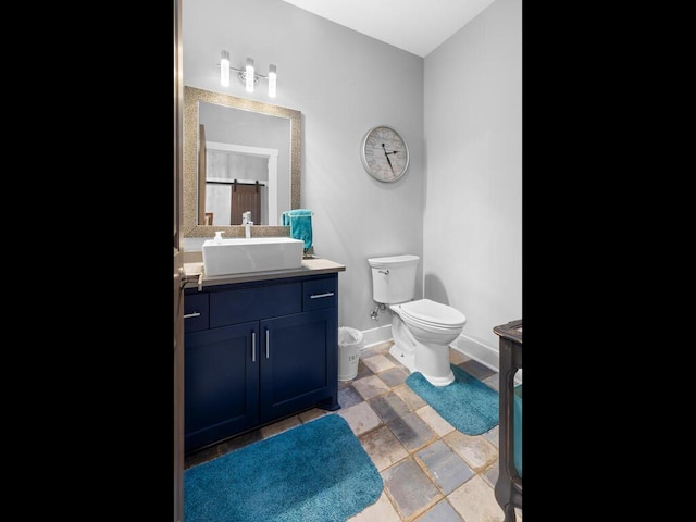 bathroom featuring toilet, baseboards, and vanity