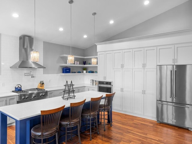 kitchen with stainless steel appliances, wood finished floors, light countertops, wall chimney exhaust hood, and open shelves