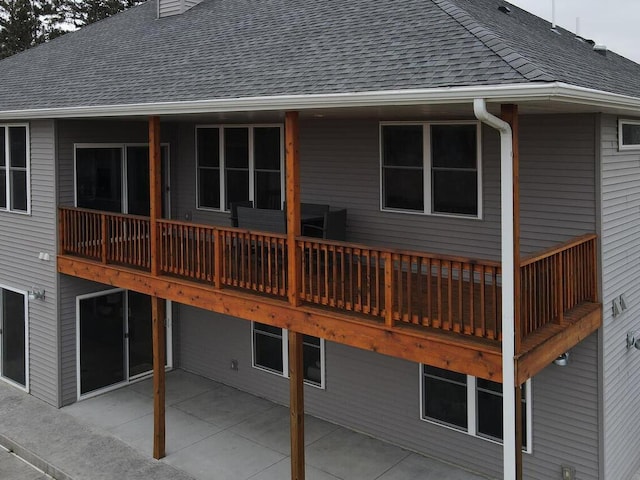 back of house featuring a patio area, a chimney, and roof with shingles