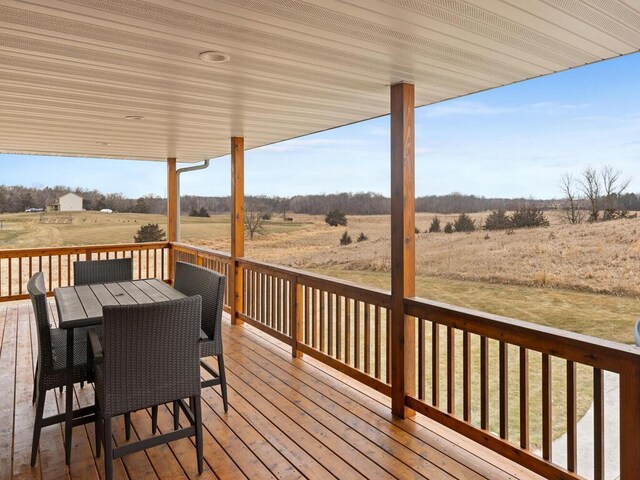 wooden terrace with a rural view and outdoor dining space