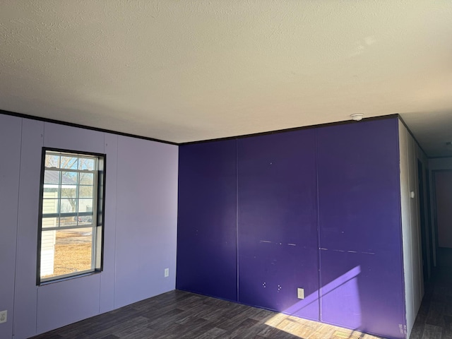 unfurnished room featuring a textured ceiling and wood finished floors