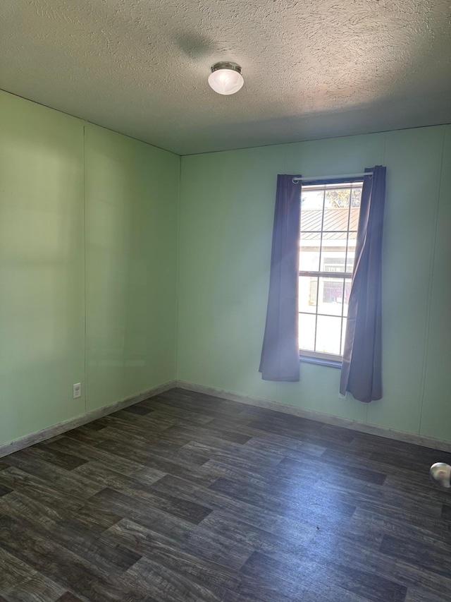 spare room featuring dark wood finished floors, a textured ceiling, and baseboards