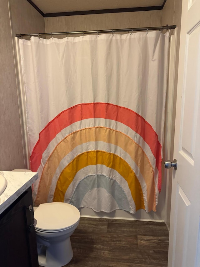 bathroom featuring toilet, a shower with curtain, ornamental molding, wood finished floors, and vanity