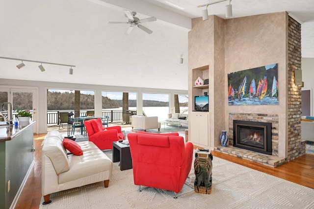 living room featuring high vaulted ceiling, a fireplace, wood finished floors, built in features, and rail lighting