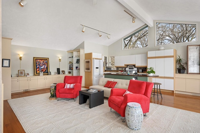 living area with rail lighting, light wood-style flooring, high vaulted ceiling, and beam ceiling