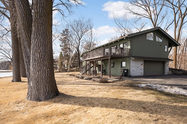 view of home's exterior with a garage, aphalt driveway, stairs, a wooden deck, and brick siding