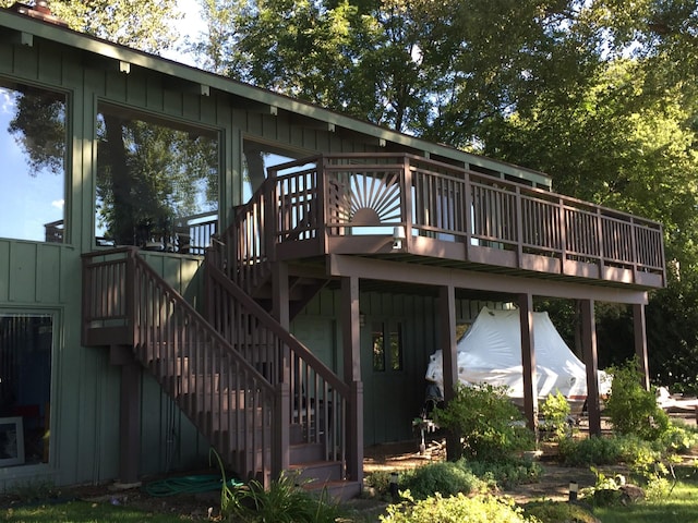 back of house with board and batten siding, stairway, and a deck