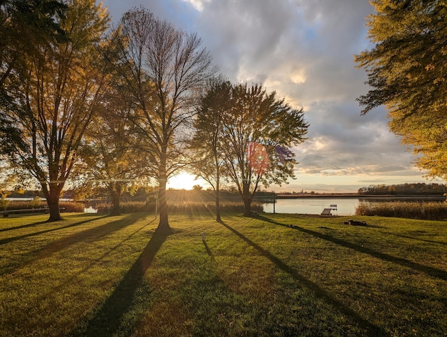 yard at dusk featuring a water view