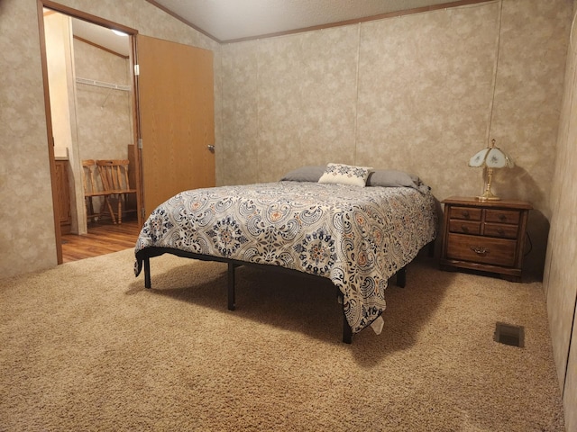 carpeted bedroom with lofted ceiling, visible vents, and crown molding