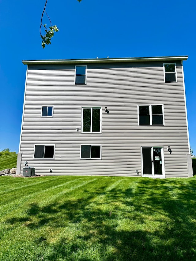 back of property with a yard and central air condition unit