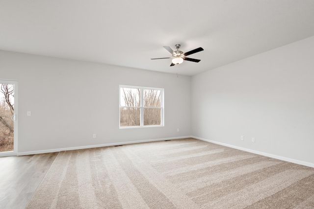 empty room featuring light wood-type flooring, visible vents, ceiling fan, and baseboards