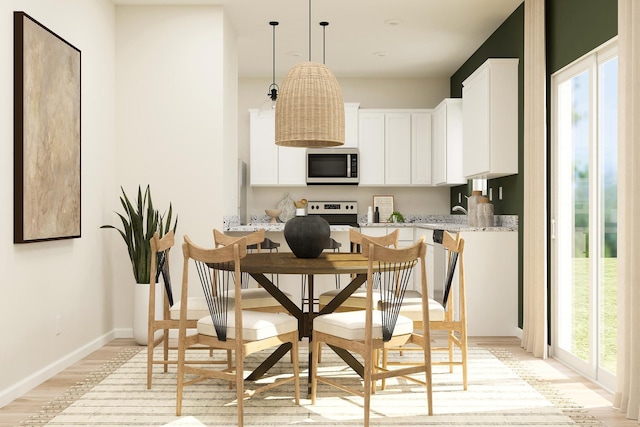 416 Tanner Dr, Waverly, MN 55390 - kitchen featuring light wood-style flooring, baseboards, stainless steel microwave, white cabinetry, and pendant lighting