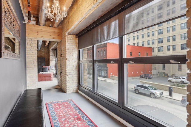 entryway featuring finished concrete flooring, brick wall, and a chandelier