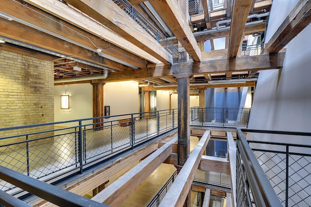 hallway with brick wall and an upstairs landing